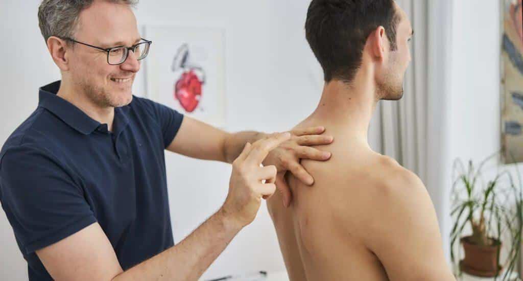 Dr. med. Markus Moser. führt einen Herzcheck bei einem Patienten in seiner Berliner Praxis durch